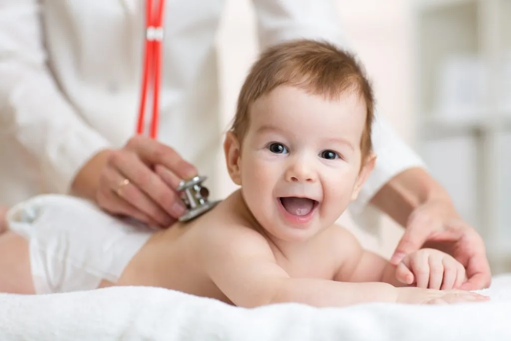 A smiling baby at a checkup with a pediatrician